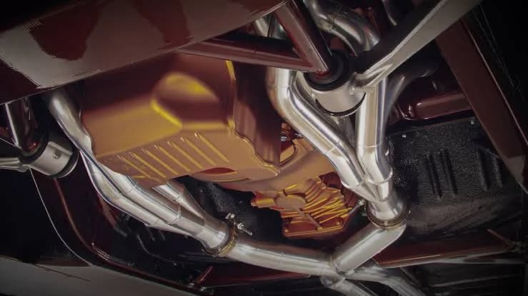 Stainless steel cat-back exhaust system mounted under a performance car build on a two-post shop lift